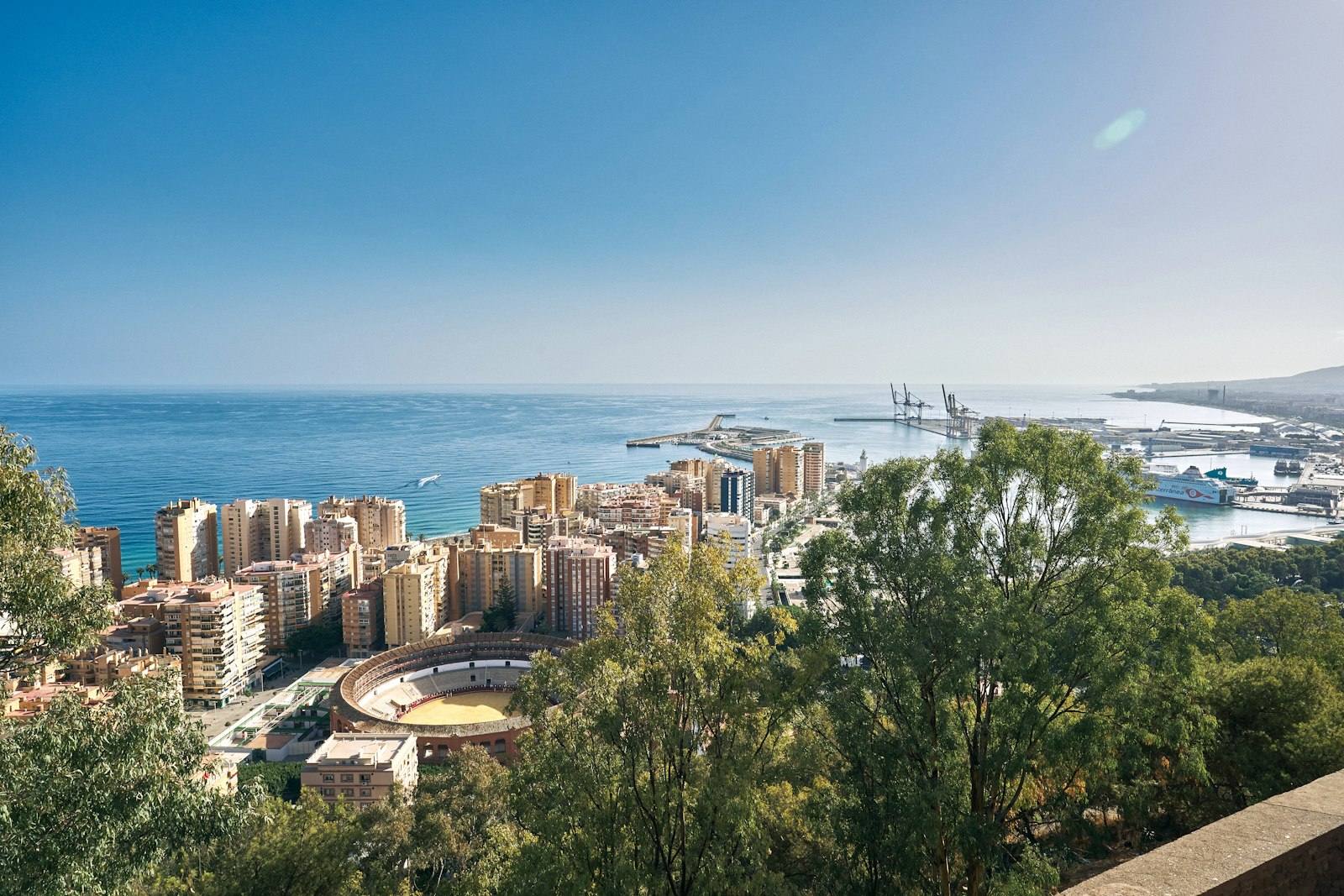 Vista aérea de Málaga con el arbolado, la ciudad y la bahía al fondo.