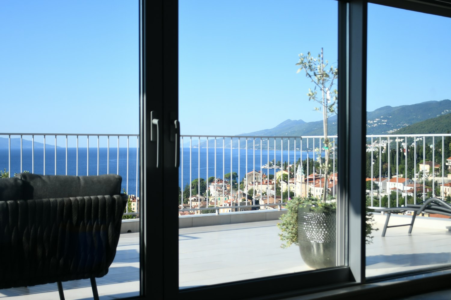 Terraza con barandilla acristalada abierta al mar y a la costa.