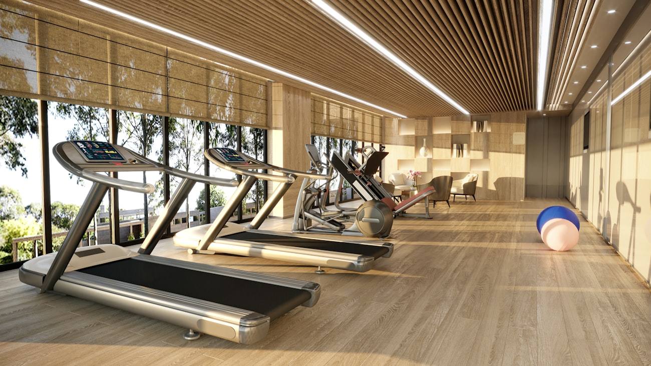 Sala de gimnasio con cintas de correr frente a grandes ventanales.