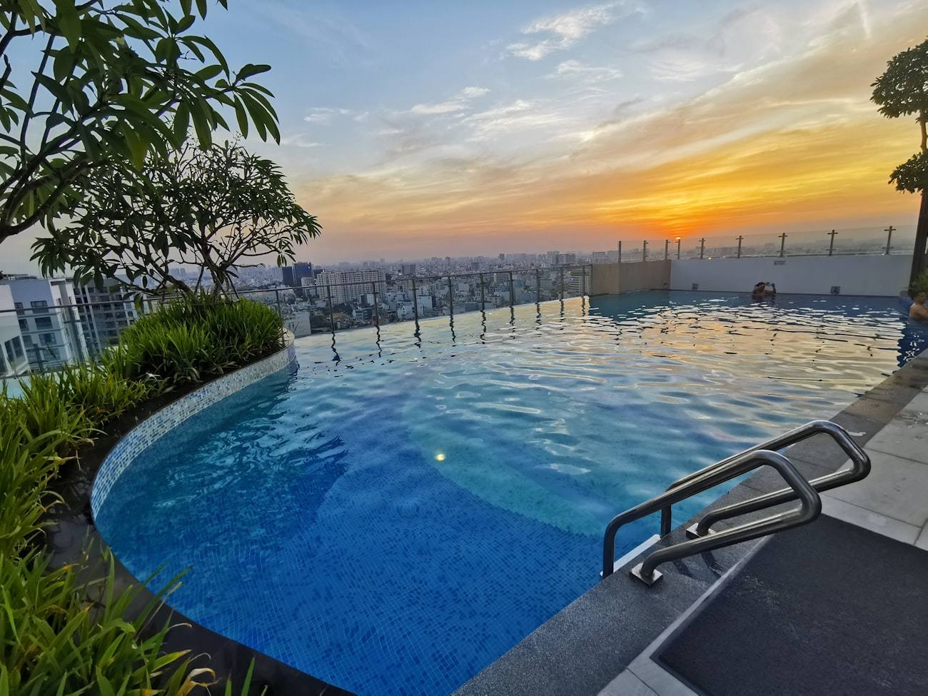 Piscina de borde infinito al atardecer sobre la bahía.