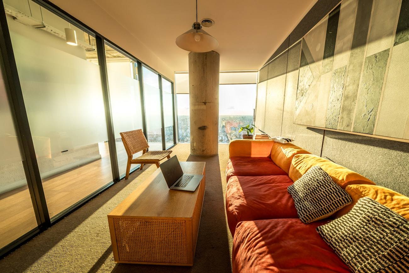 Sala común con sofás, mesas bajas y ventanales al jardín.
